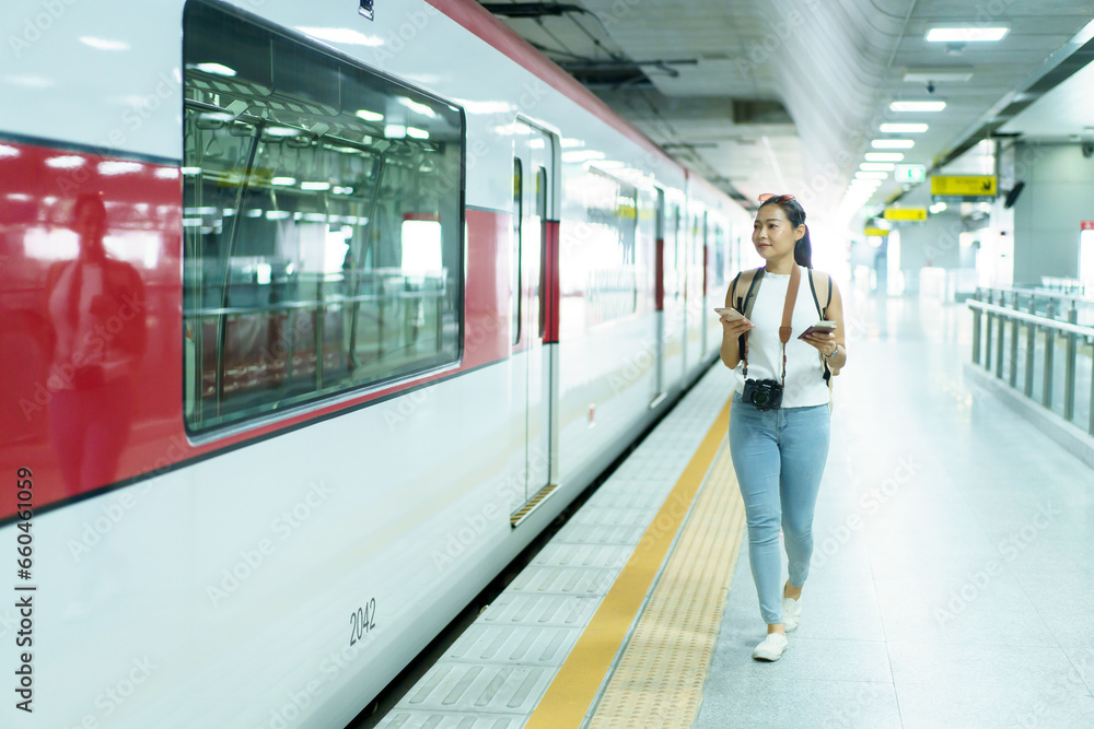 Happy beautiful Asian woman waiting for a train at railway platform. Lonely Asian female tourist or traveler standing at train station. Happy beautiful Asian woman waiting for a train at railway platform. Lonely Asian female tourist or traveler standing at train station.