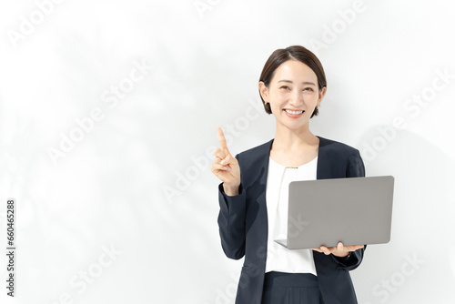 ノートパソコンを持って指差しをビジネスウーマン