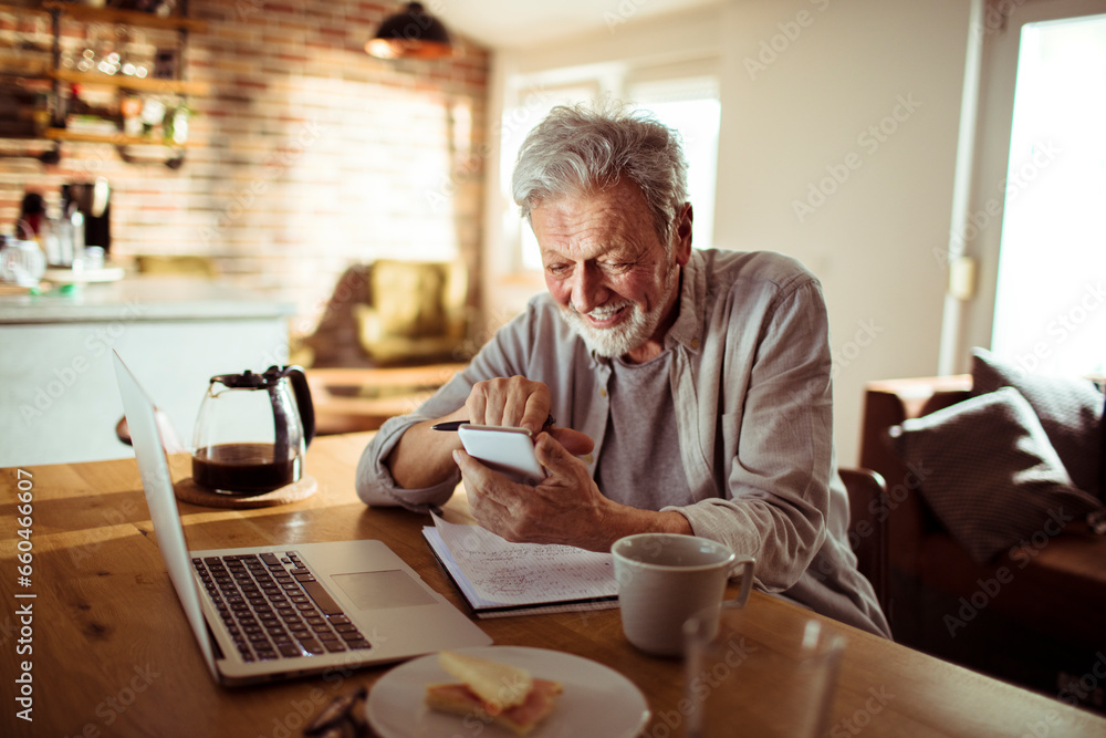 Senior man using a smartphone at home - obrazy, fototapety, plakaty 