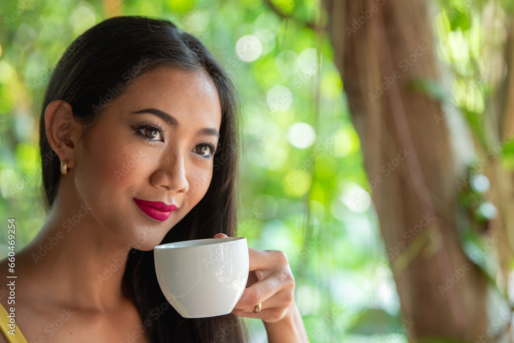 Asian woman holding hot coffee in paper mug cup to sniff smell of espresso in morning sunlight. girl carry coffee break to sniff fragrant smell the aroma of coffee. Asian woman holding hot coffee in paper mug cup to sniff smell of espresso in morning sunlight. girl carry coffee break to sniff fragrant smell the aroma of coffee.