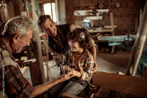 Multigenerational family of male carpenters teaching their youngest one the ways in a carpentry shop