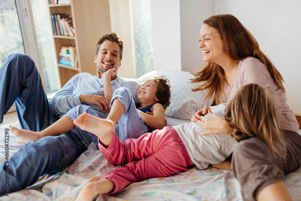 Happy young family playing and having fun on the bed at home Happy young family playing and having fun on the bed at home