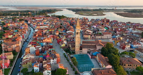 Aerial view shot of the Church of Saint Martin Bishop and Campanile Pendente on Burano Island near Venice, with colorful houses, Italy at sunrise