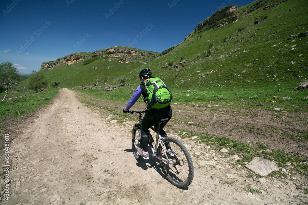 A young woman on a bicycle in the Caucasus mountains, Russia.