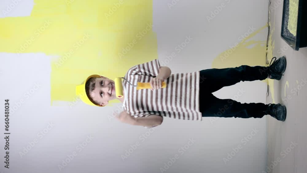 Cute boy with a paint roller sings while painting a wall. Happy kid helps parents to paint wall. Home renovation. Cute boy with a paint roller sings while painting a wall. Happy kid helps parents to paint wall. Home renovation.