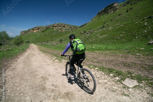 A young woman on a bicycle in the Caucasus mountains, Russia.