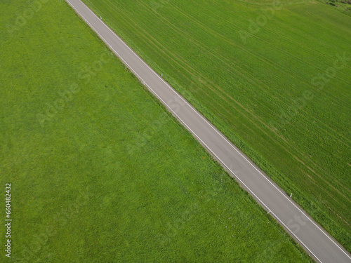 Aerial view of a road between grass fields in the landscape 