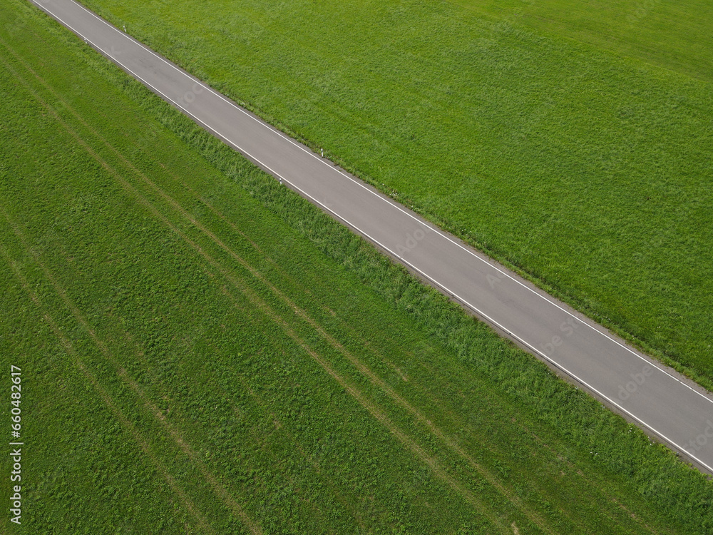 Obraz premium Aerial view of a road between grass fields in the landscape