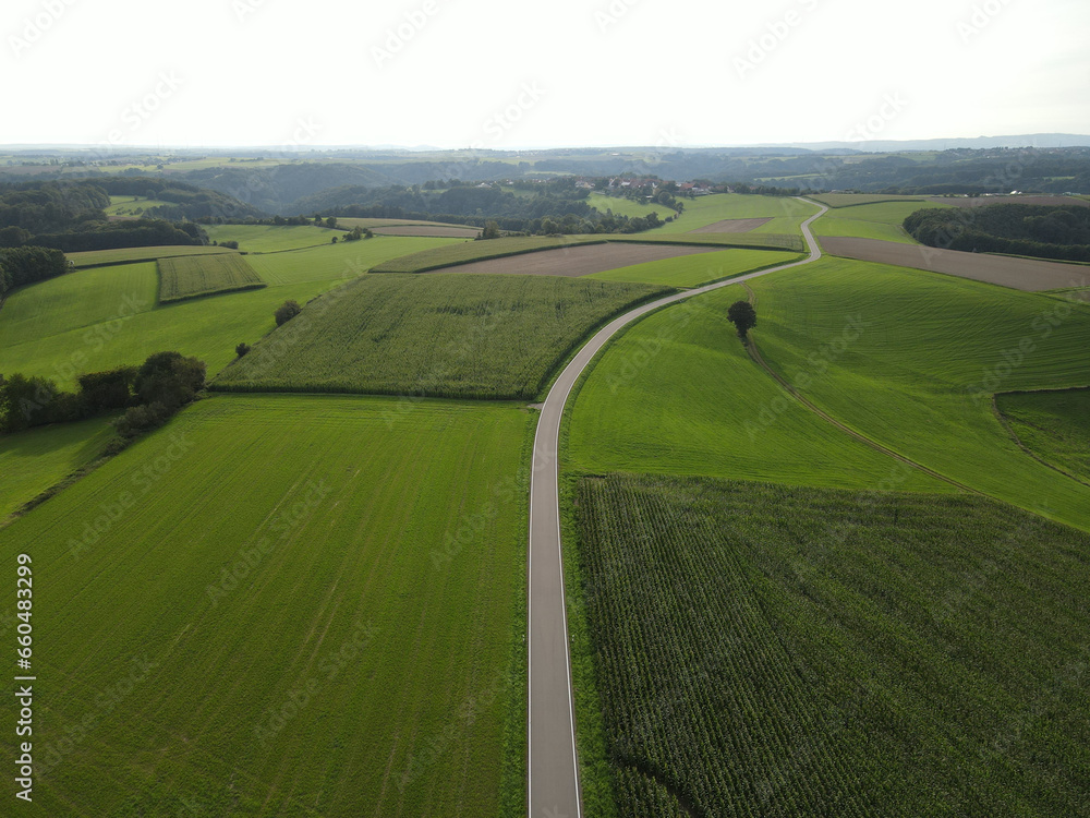 Aerial view of a long rural road between fields in the landscape 