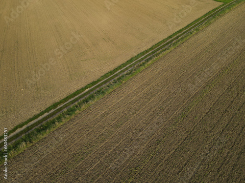 View from above of plowed fields with a country road in the middle 