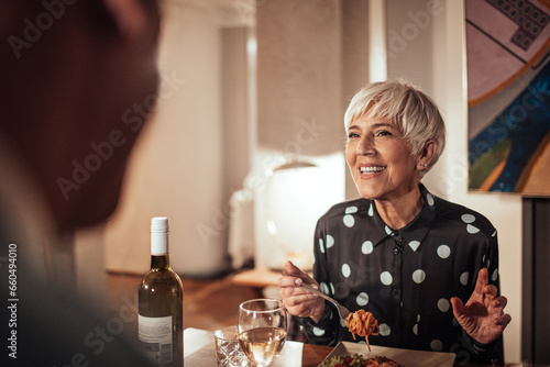 Senior woman having wine and dinner with her husband at home photo