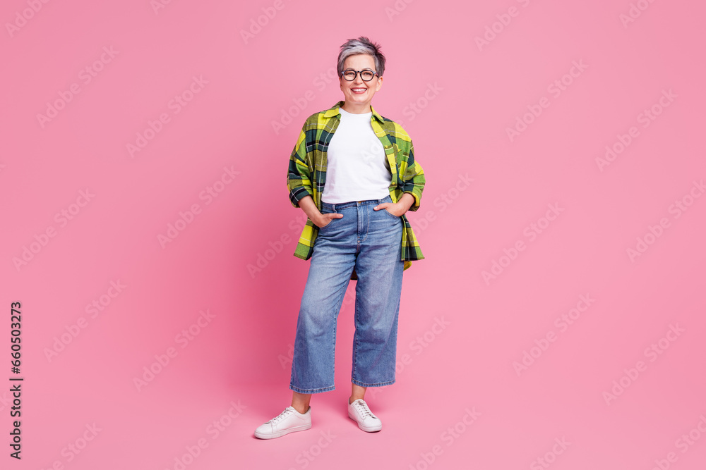 Full size photo of optimistic person with white gray hairdo dressed plaid shirt hold hands in pockets isolated on pink color background Full size photo of optimistic person with white gray hairdo dressed plaid shirt hold hands in pockets isolated on pink color background