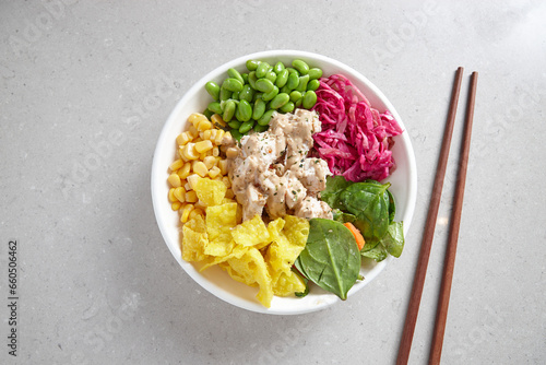 top shot of a bowl of chicken vegetable salad with wooden chopsticks on top grey background photo