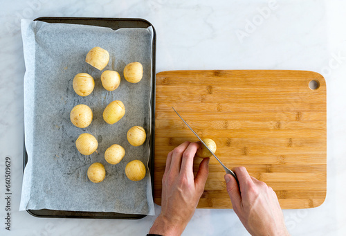 Top down of hands carefully slicing potatoes on bamboo chopping board photo