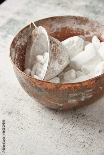 Bowl of lumpy icing sugar with sieve