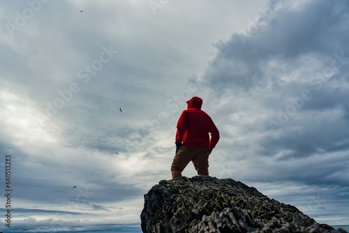 Foto Male hiker standing confront with birds on the rock