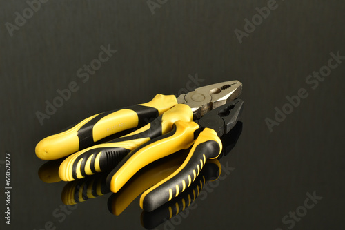 Foto Mechanic's tools: ordinary pliers with yellow handles.