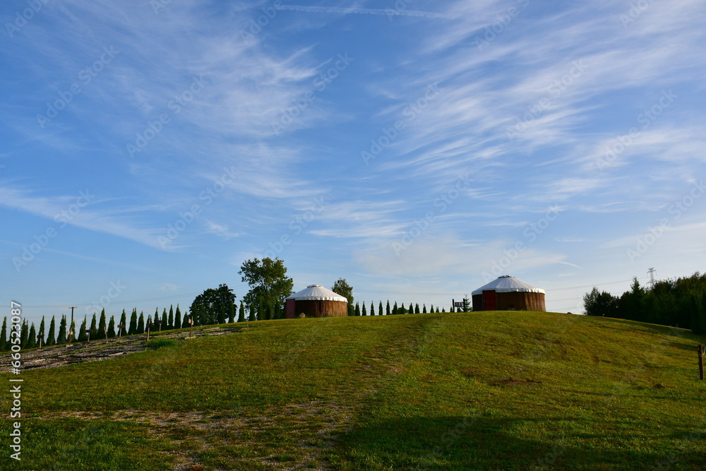 A close up on two temporary houses or huts similars to the ones used and built by nomadic tribes located on the top of a hill, next to a wooden fence, spotted on a cloudy summer day in Poland A close up on two temporary houses or huts similars to the ones used and built by nomadic tribes located on the top of a hill, next to a wooden fence, spotted on a cloudy summer day in Poland