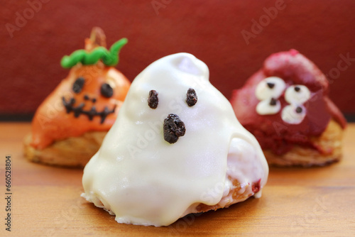 Three of Halloween Ghosts Shaped Sugar Glazed Croissants on Wooden Background