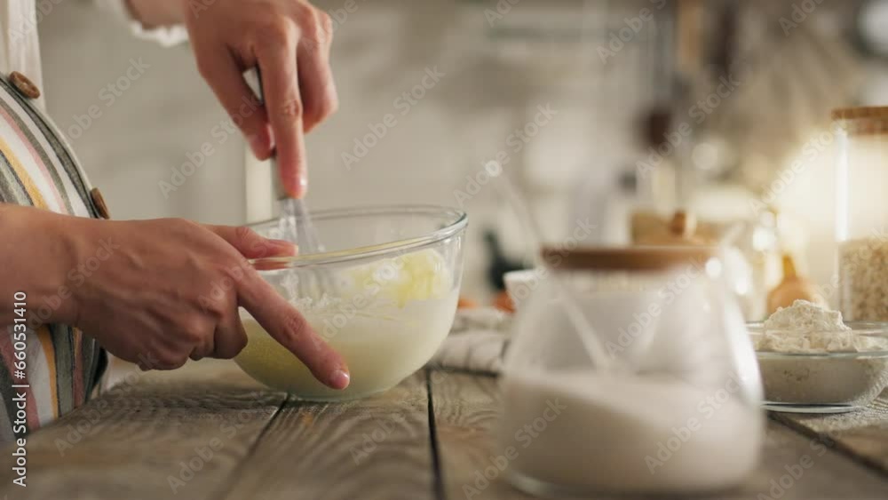 Oats. A mature woman in kitchen clothes prepares homemade cakes in the kitchen on a wooden table. Attentive housewife bakes oatmeal cookies at home, applies new mixing of ingredients, melted Oats. A mature woman in kitchen clothes prepares homemade cakes in the kitchen on a wooden table. Attentive housewife bakes oatmeal cookies at home, applies new mixing of ingredients, melted