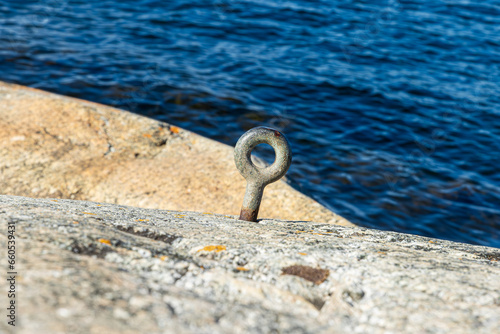 An old iron loop in granite rock for tying up boats