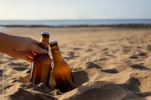 Deux bières sur la plage, une main tendue. photo