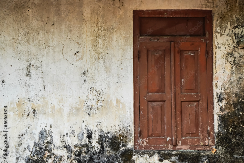 Closed old Javanese wooden window with shutters on an moldy white concrete wall. Concept for traditional exterior, vintage, heritage, rural housing ornament. Empty blank copy text space. Omah Joglo Closed old Javanese wooden window with shutters on an moldy white concrete wall. Concept for traditional exterior, vintage, heritage, rural housing ornament. Empty blank copy text space. Omah Joglo