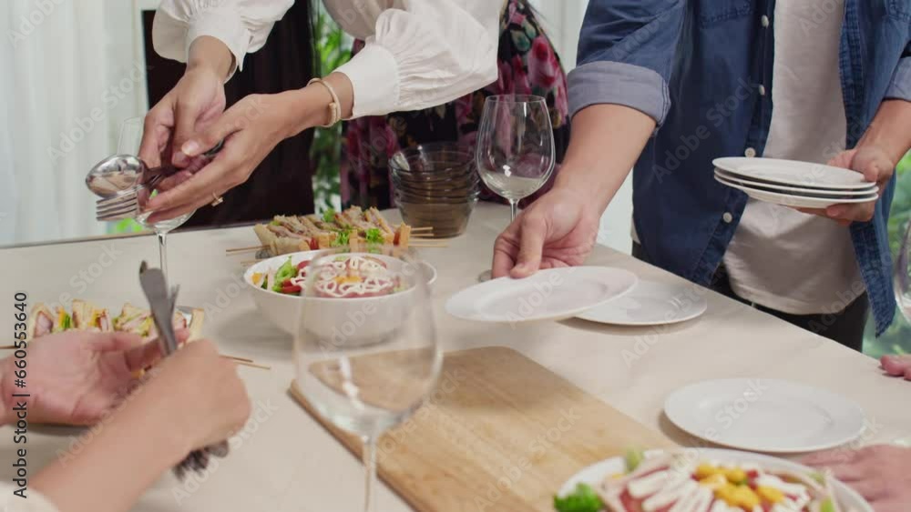 Cropped shot of unrecognizable people setting table with festive dishes while preparing for celebration Cropped shot of unrecognizable people setting table with festive dishes while preparing for celebration