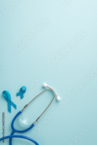 Fototapeta Naklejka Na Ścianę i Meble -  Emphasize importance of men's health month with top view vertical image displaying blue ribbons and a stethoscope for health examinations on a pastel blue background, offering space for text