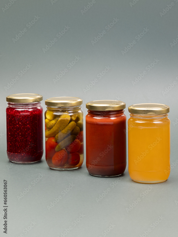 Group of jars with honey , marinated tomatos and gherkins tomato sauce and raspberry jam on plain background. Various ingredient. Group of jars with honey , marinated tomatos and gherkins tomato sauce and raspberry jam on plain background. Various ingredient.