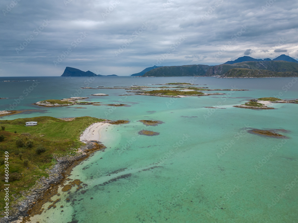 Obraz premium High angle view of archipelago on turqouise ocean. Rocky mountains on a background. Coast of Sommaroy in Norway.