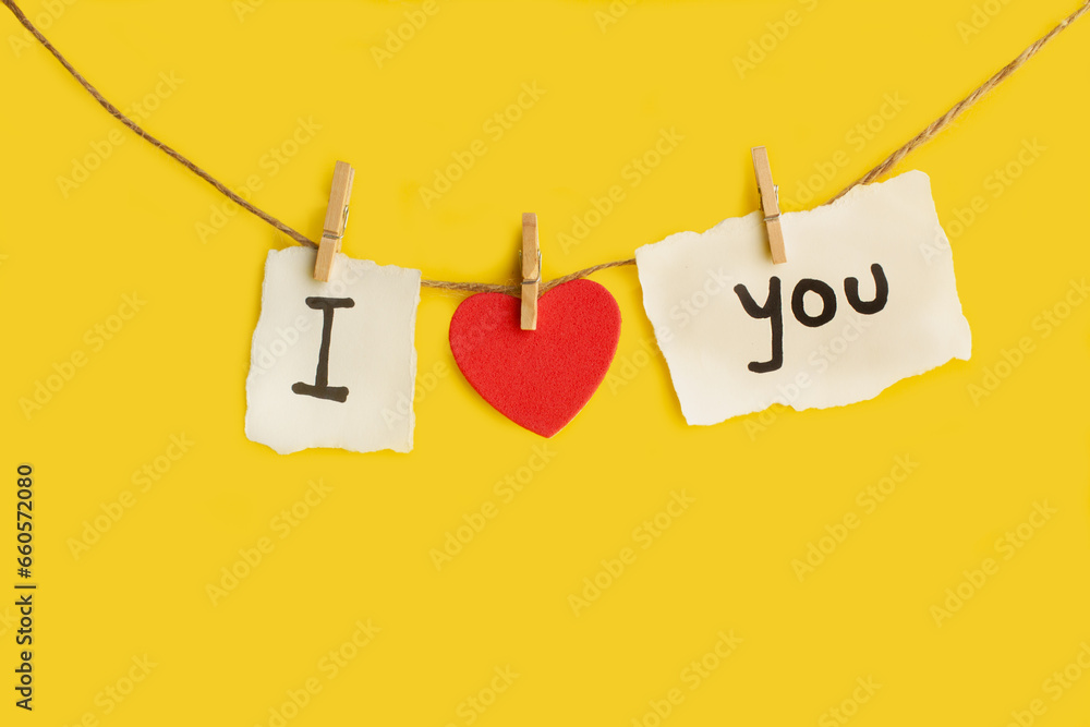 Un cartel colgado con la palabra I love you sobre un fondo amarillo liso y aislado. Vista de frente y de cerca. Copy space - obrazy, fototapety, plakaty 