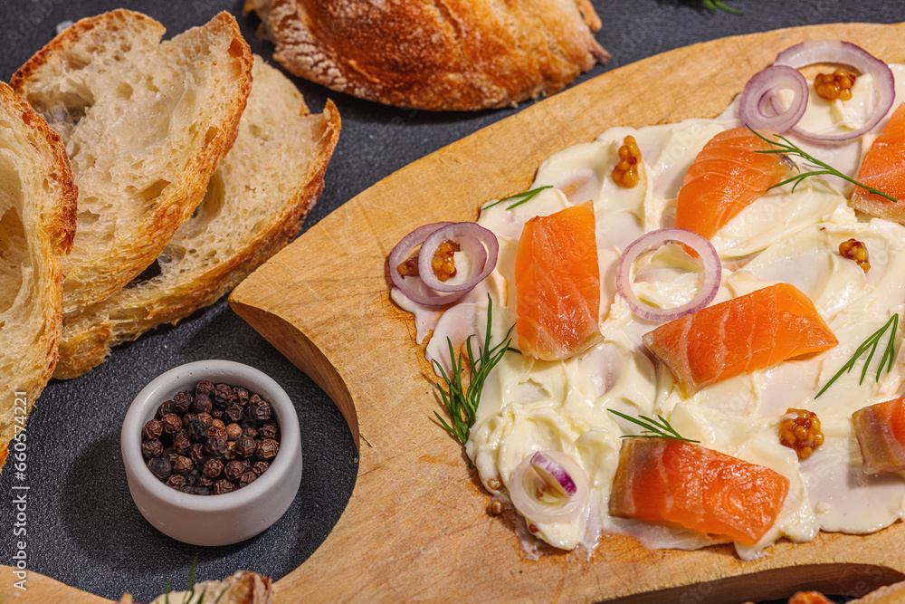 Butter Board food trend topped with salmon, shallots and fresh greens. Appetizer for party, baguette