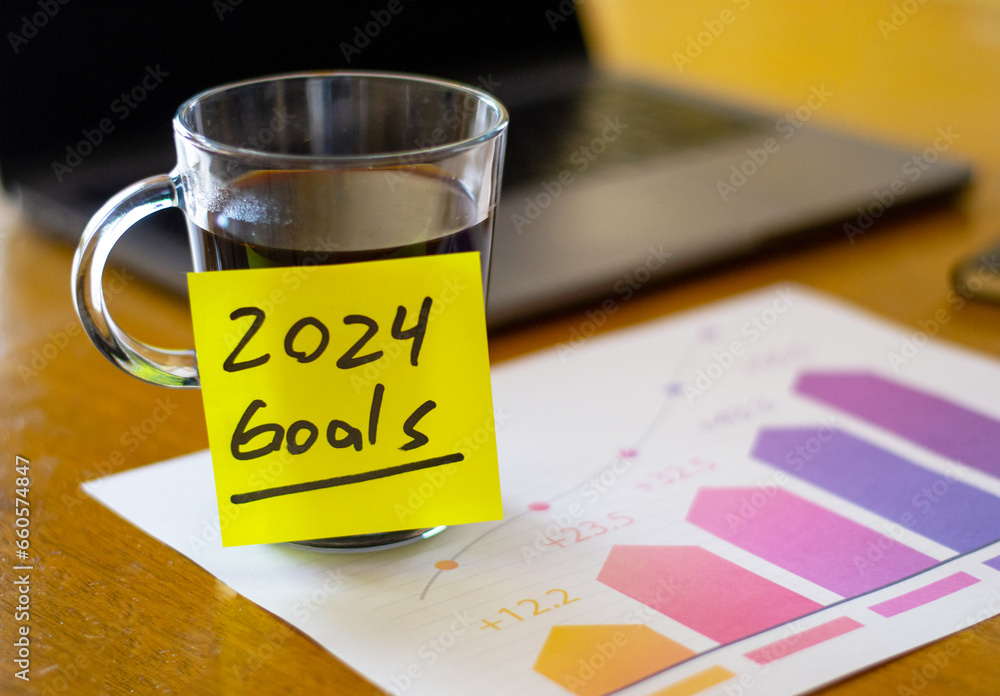 new year resolution concept. Cup of coffee with a note of goals on a growth chart, laptop in the background new year resolution concept. Cup of coffee with a note of goals on a growth chart, laptop in the background