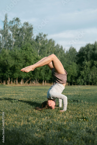 Adult female practising yoga outside, forearm balance pose pincha mayurasana