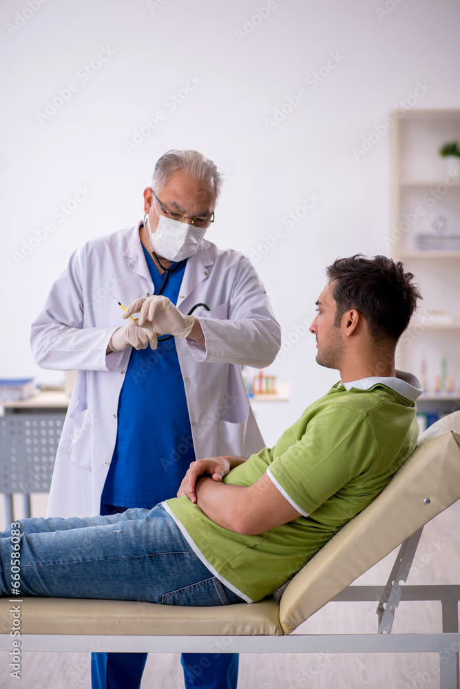 Obraz premium Young male patient visiting old male doctor in vaccination conce