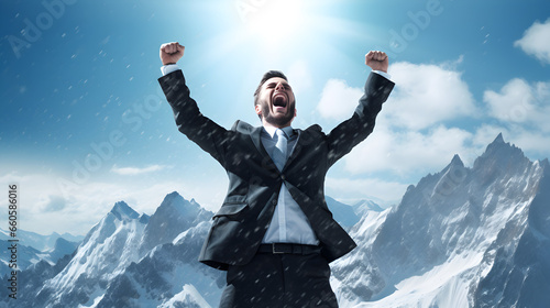 un homme en costume, les bras en l'air en signe de victoire, au sommet d'une montagne enneigée