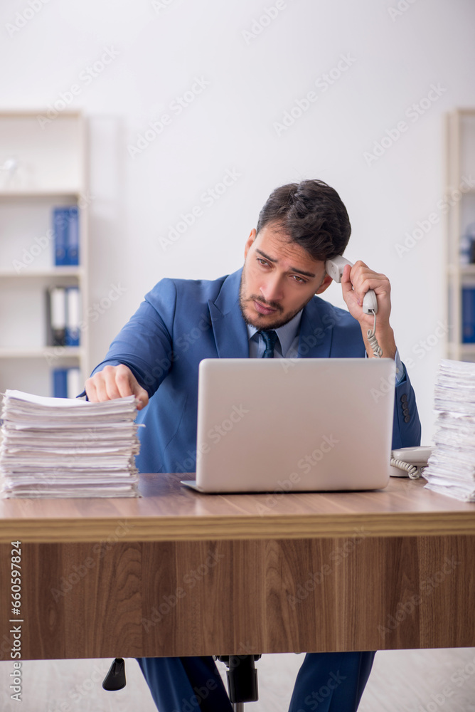 Young male employee and too much work in the office Young male employee and too much work in the office