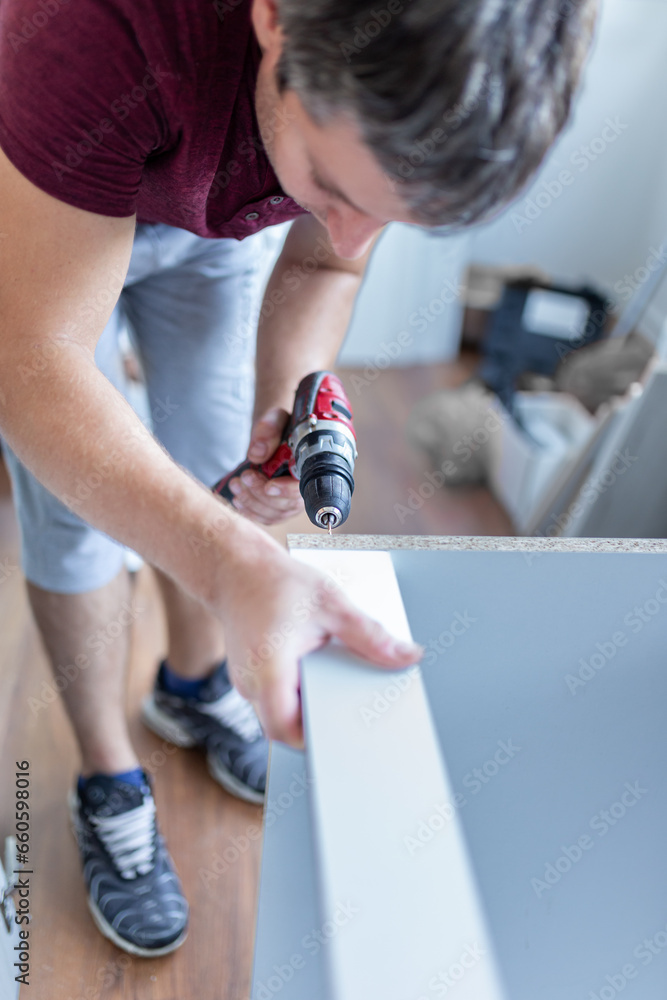 Obraz premium Male Using Self-Assembly Kit Making Cabinet