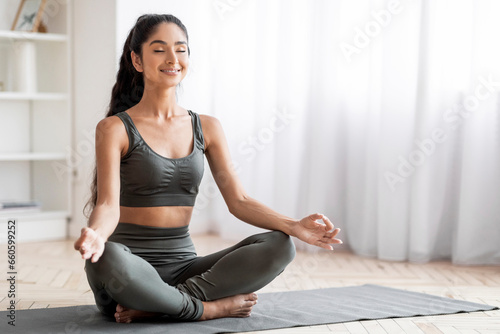 Peaceful young eastern woman meditating at home