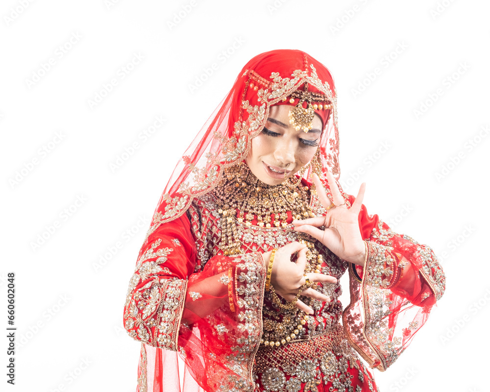Close up portrait of a beautiful Asian Muslim lady in a hijab wearing a gorgeous Bollywood or Indian themed red traditional wedding dress isolated on white background