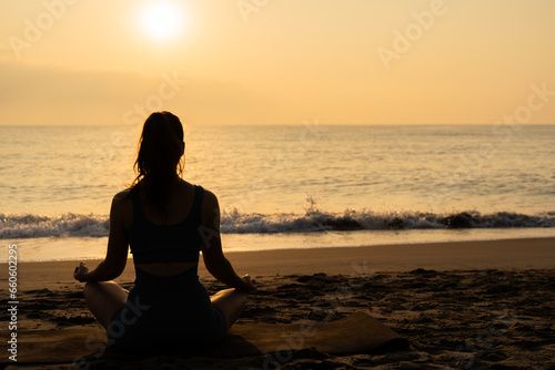 meditation and yoga on the beach. concept of doing yoga by the sea. woman in lotus position at dawn © pablo