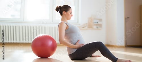 Young pregnant woman doing exercises with fitball