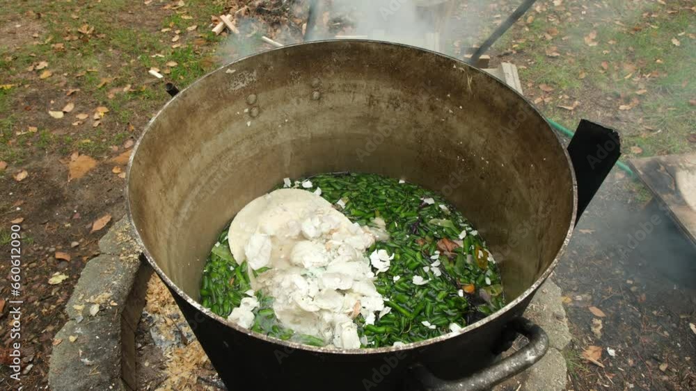 Green beans ends or trims and egg shells and other food leftovers being cooked in large pot over fire pit while preparing animal feed. Green beans ends or trims and egg shells and other food leftovers being cooked in large pot over fire pit while preparing animal feed.