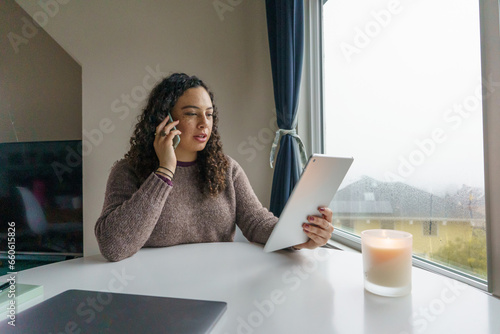 Curly hair young woman working on laptop in cozy nook with mug	