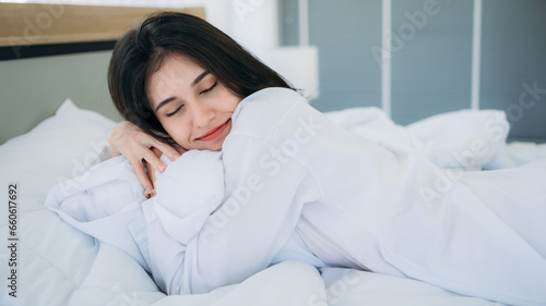 Young Woman Waking Up with Happiness in Cozy Bedroom at Home. Beautiful Girl Smiling and Relaxing in Bed after Waking Up.