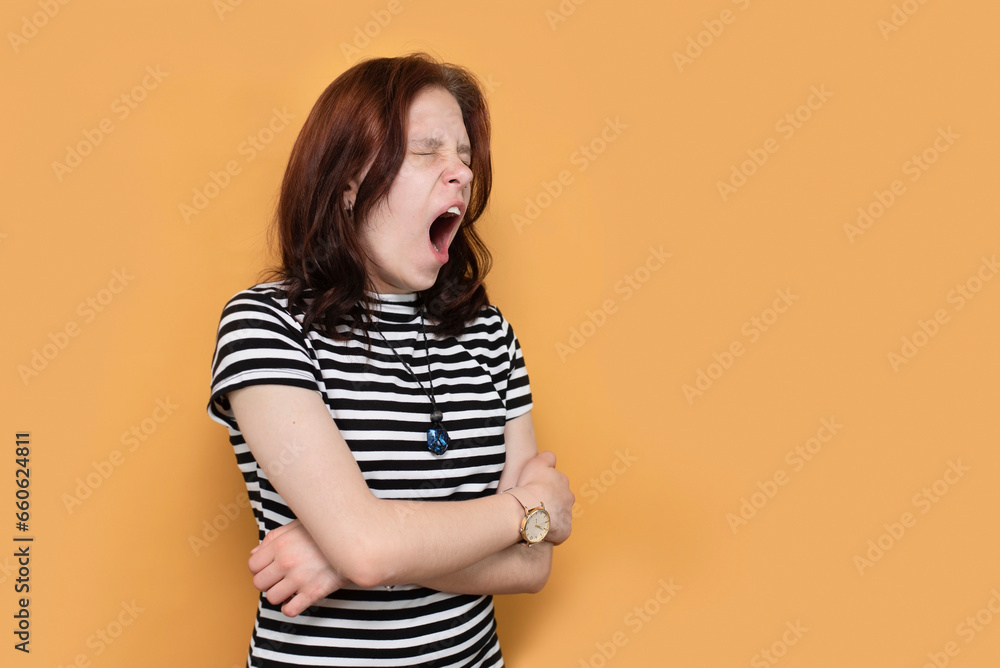 Teenage girl is very tired from studying in college and from homework and yawning on orange background, natural yawn from tiredness and lack of sleep Teenage girl is very tired from studying in college and from homework and yawning on orange background, natural yawn from tiredness and lack of sleep