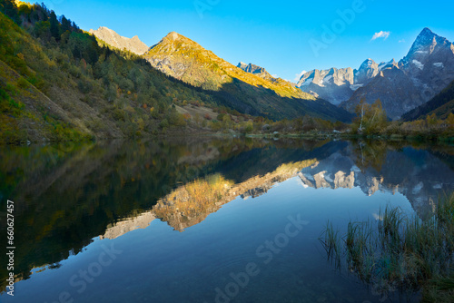 Autumn. A picturesque mountain lake with clear water surrounded by mountains. Mountain relief and blue sky are reflected in the water. Copy space.