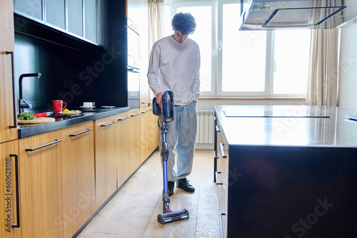 Young guy doing vacuuming at home