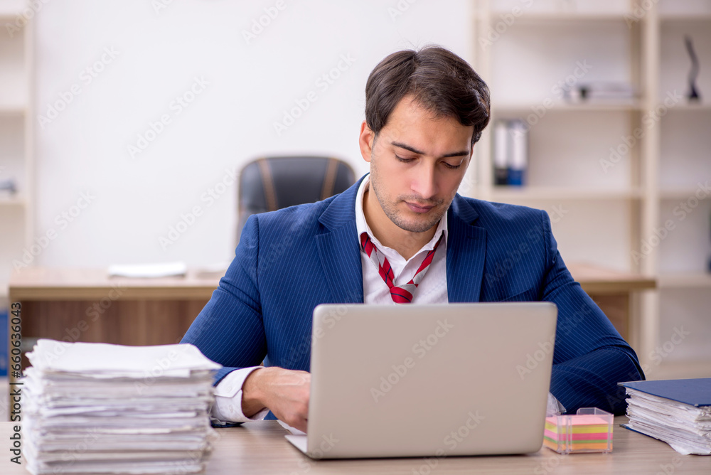 Young male employee and too much work in the office Young male employee and too much work in the office